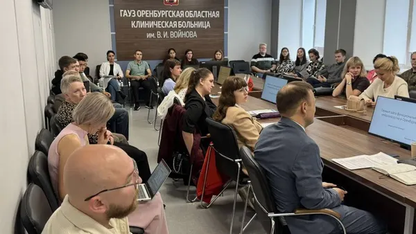 Зал сбоку: врачи за столами под вывеской областной клинической больницы