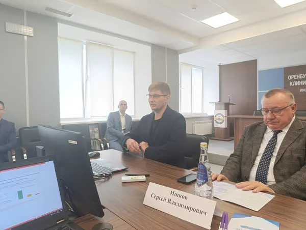 Молодой врач выступает с места, ведущий просматривает программу конференции
