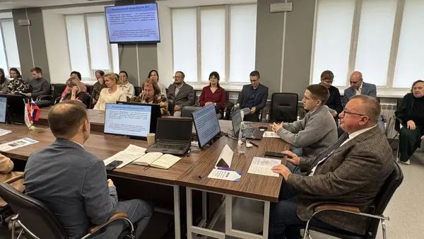 Стол докладчиков и слушатели в зале, на экране слайд презентации