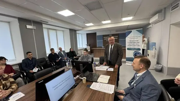 Ведущий у баннера конференции обращается к участникам за столами